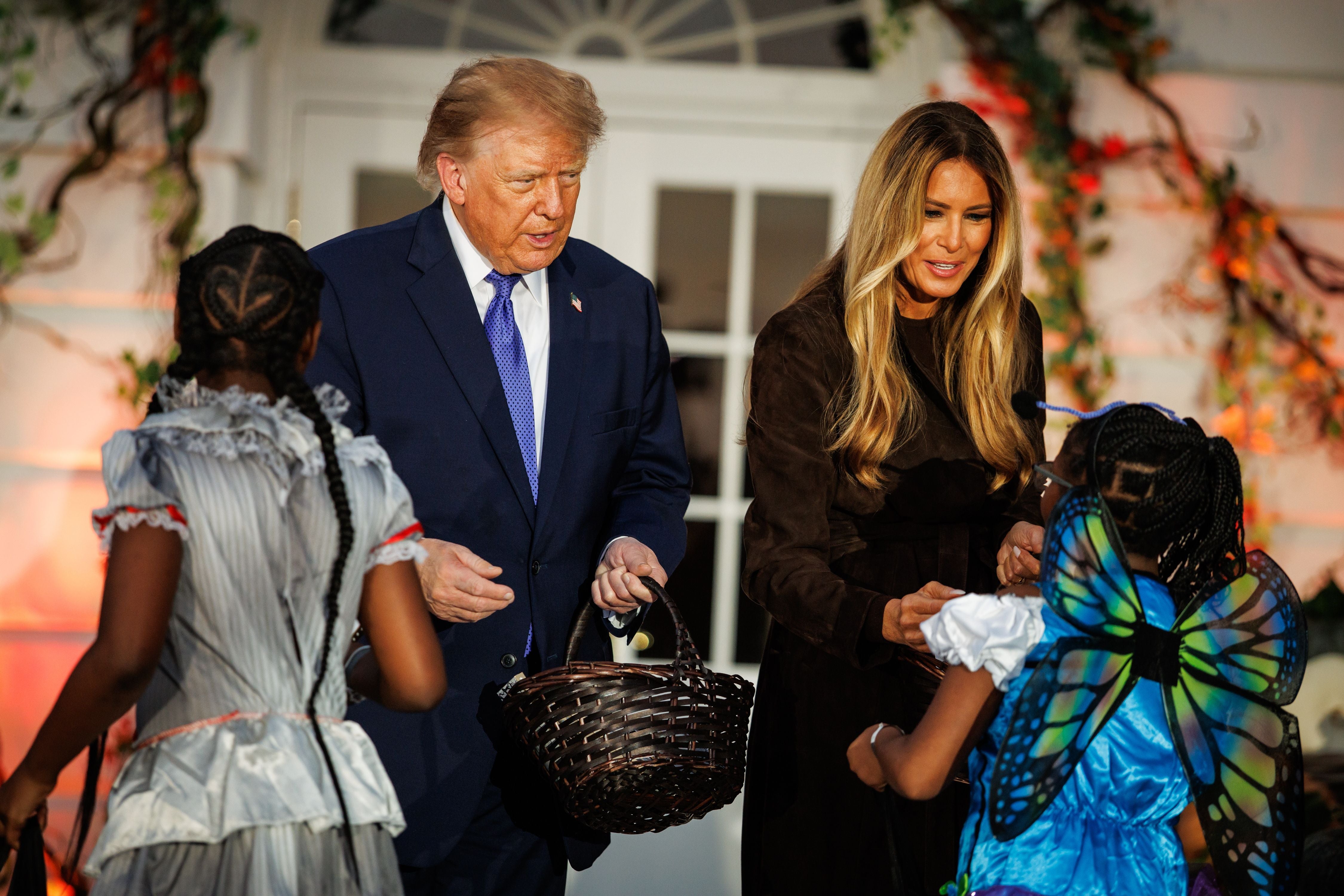 Donald Trump und Melania Trump geben Kindern in Kostümen Halloween-Süßigkeiten vor dem Weißen Haus.
