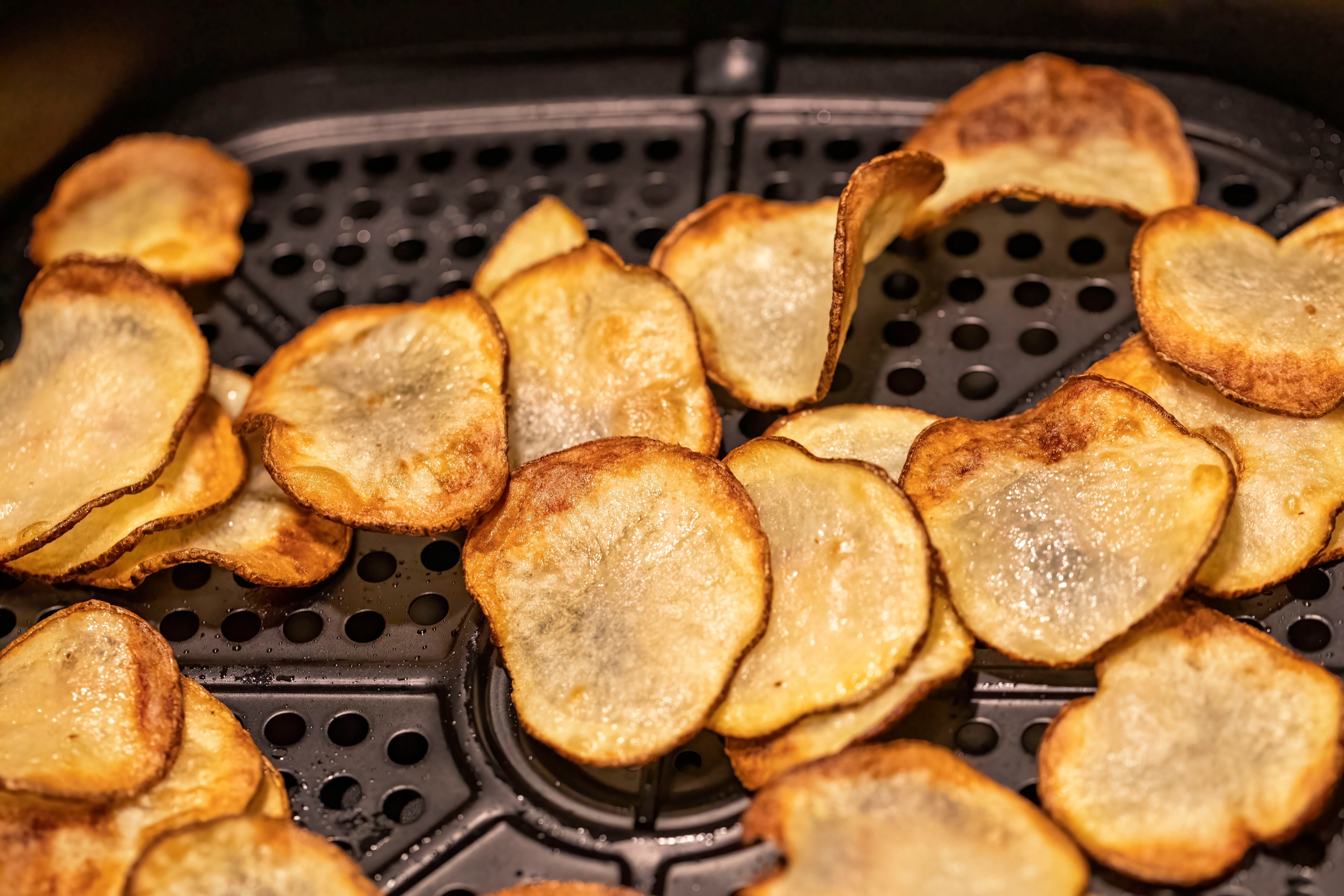 Dünne Kartoffelscheiben werden im Airfryer zu Chips gebacken.