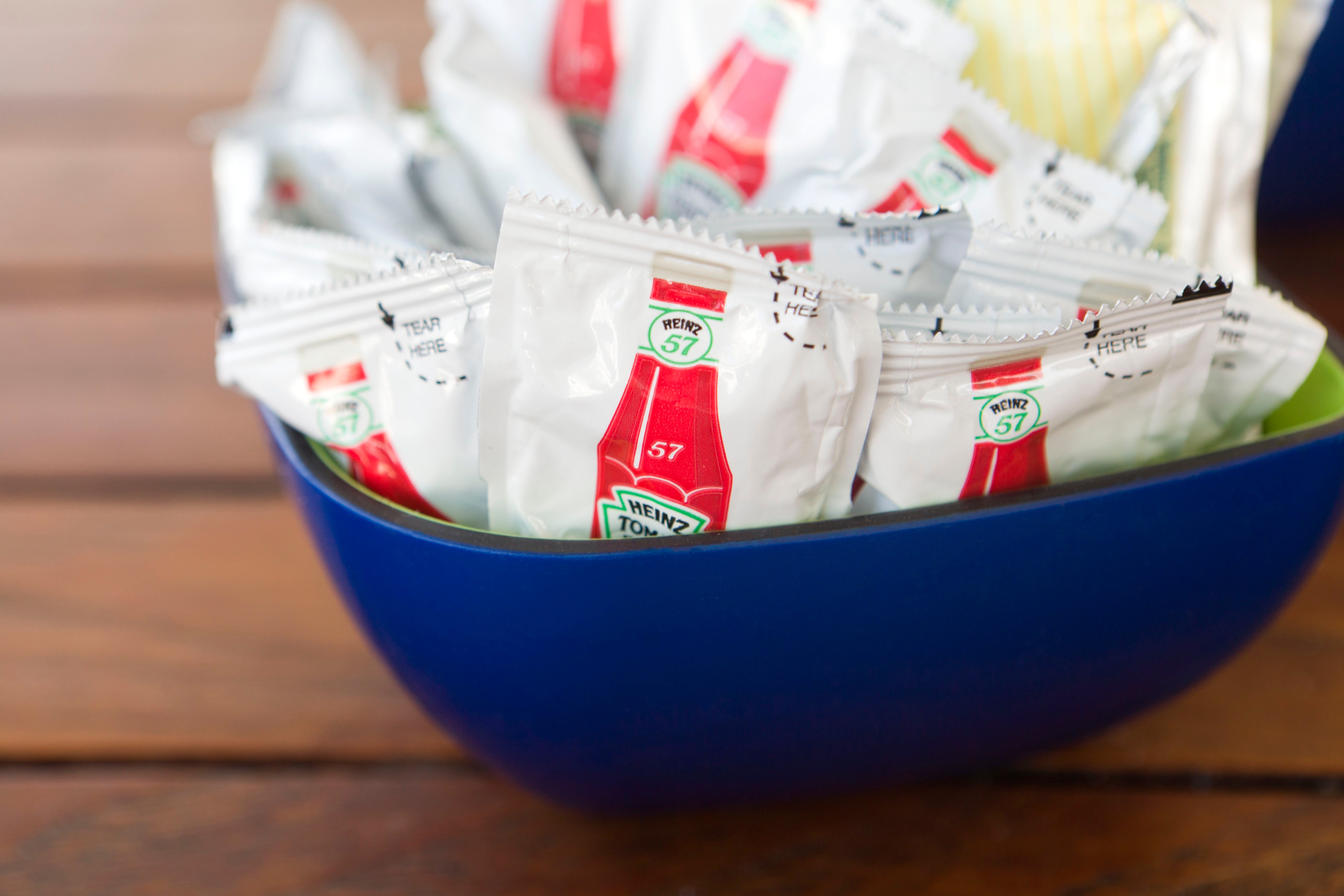 Schale mit Heinz 57 Ketchup-Portionsbeuteln auf einem Holztisch im Restaurant.