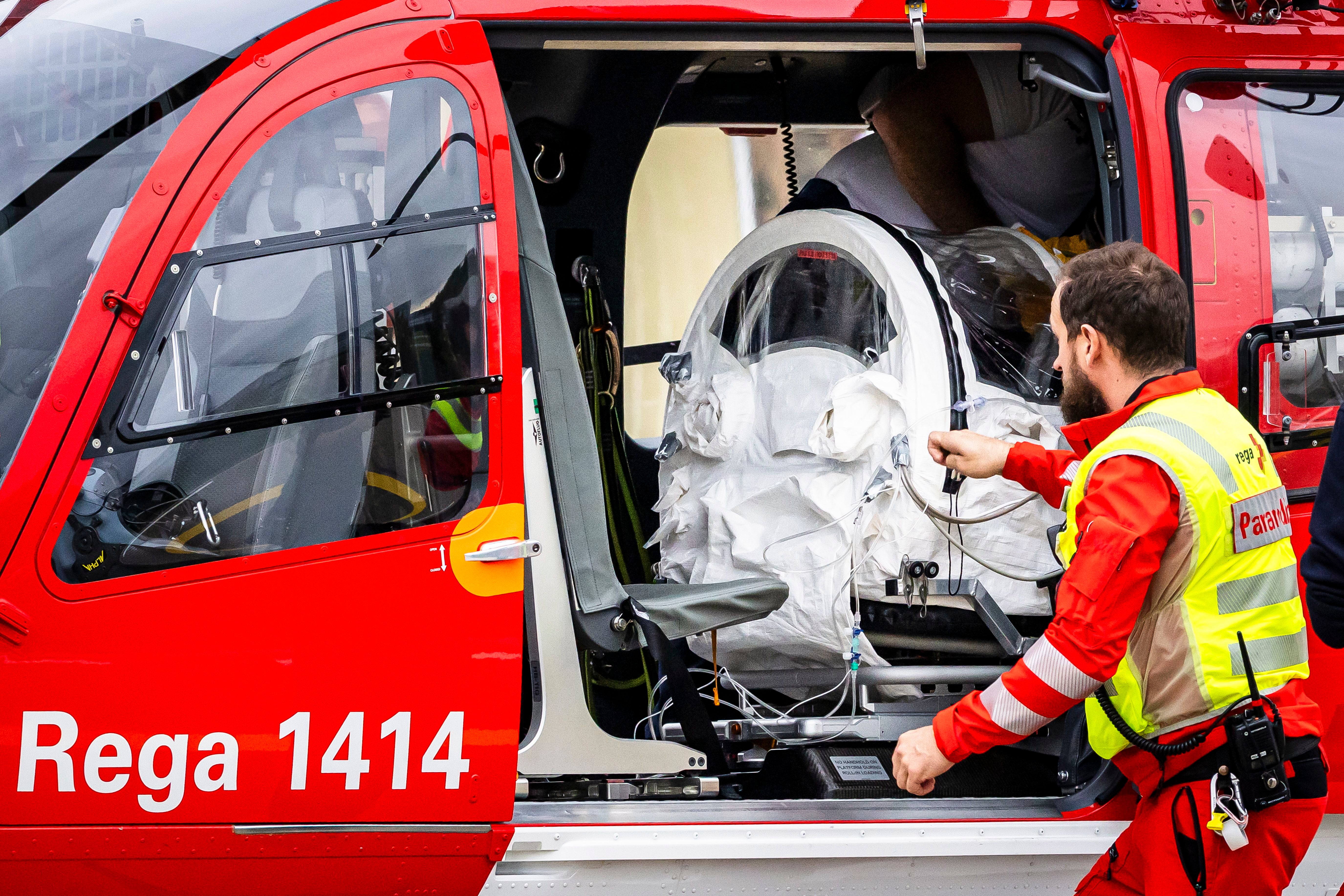 Ein Patient wird in einer Isolationskammer in einen Rega-Rettungshubschrauber verladen.