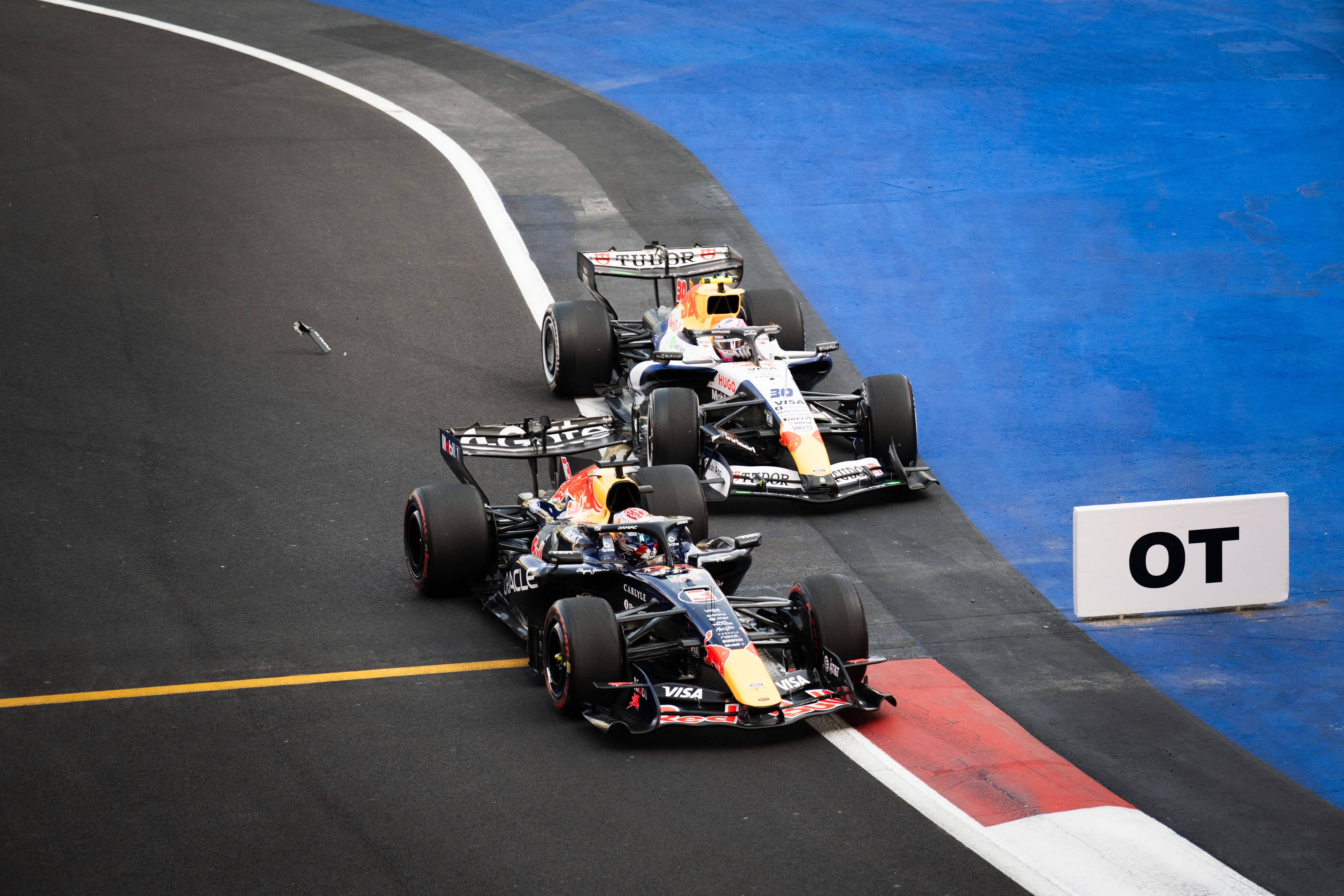 Zwei Formel-1-Autos von Red Bull und Racing Bulls fahren eng nebeneinander auf der Rennstrecke.