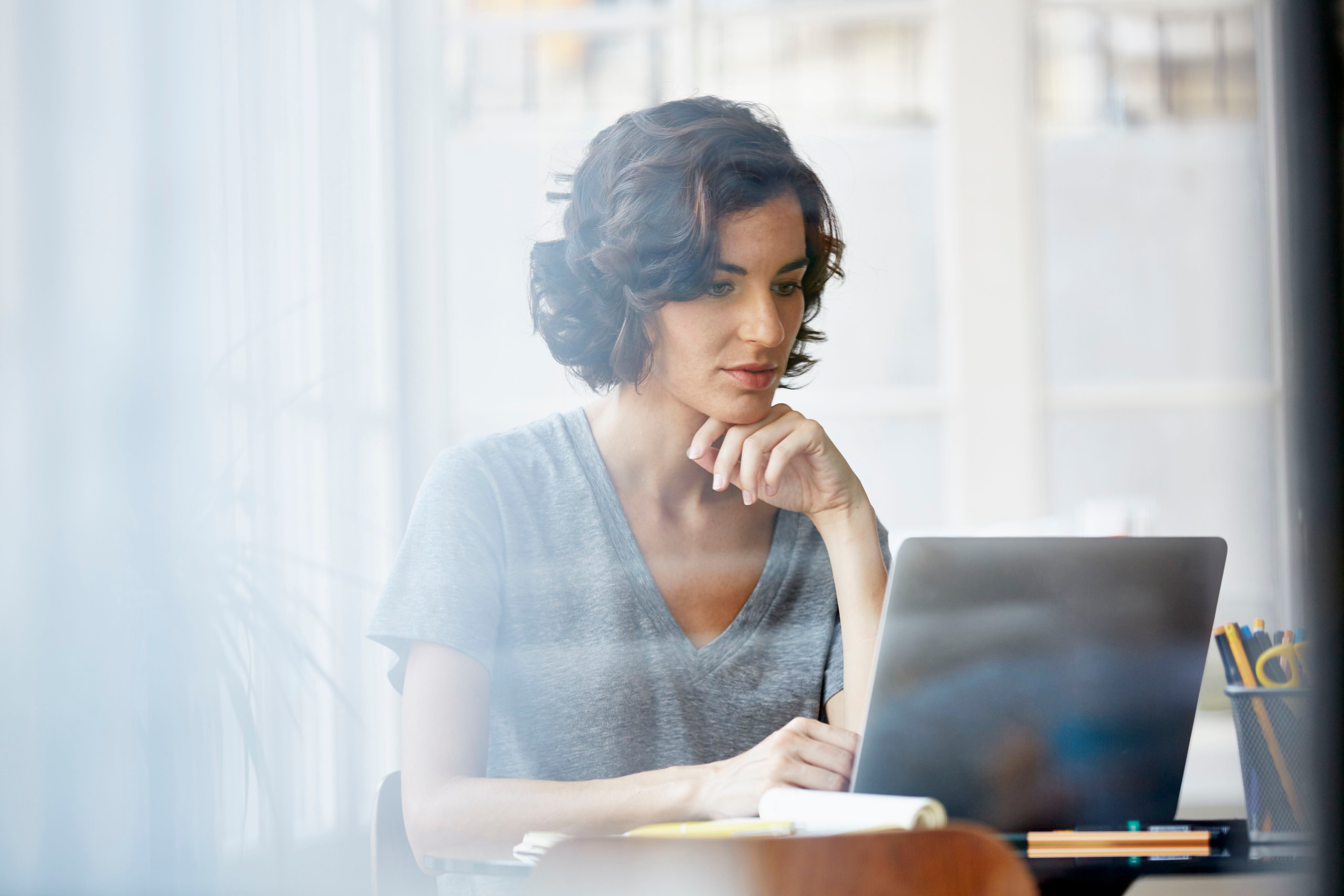 Junge Frau arbeitet konzentriert am Laptop in einem modernen Büro.